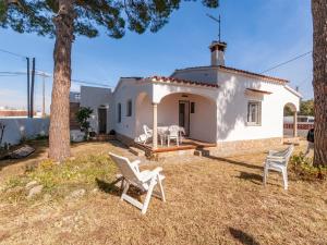 una pequeña casa blanca con sillas blancas en el patio en Belvilla by OYO Los Pinos, en L'Escala
