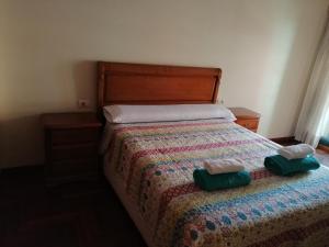 a bedroom with a bed with two green towels on it at Rotonda da Pedra Alta Apartamento in Cangas de Morrazo