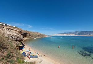 a group of people on a beach in the water at Apartmani Ivana in Novalja