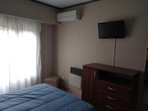 a bedroom with a bed and a dresser with a television at Departamento Maru in Tandil