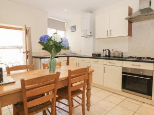 a kitchen with a wooden table with a vase of flowers at Cooper's Cottage in Pickering