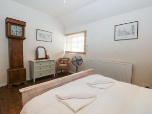 um quarto com uma cama, um relógio e uma cadeira em Cooper's Cottage em Pickering