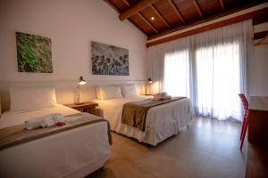 a hotel room with two beds and a window at Pousada Alto da Pipa in Pipa