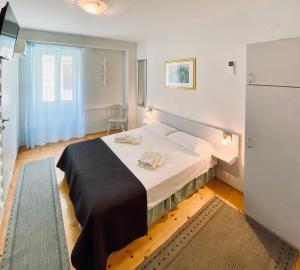 a bedroom with a bed in a room with a refrigerator at Komiza Provita Guesthouse in Komiža