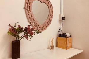 a mirror on a white shelf with a vase with flowers at RusticSecretGarden田园民宿NearJONKERAFAMOSA鸡场街红屋 by Myplace in Melaka