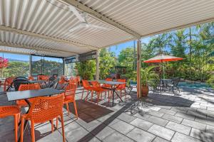 un patio con tavoli, sedie e ombrellone di Amaroo At Trinity a Trinity Beach