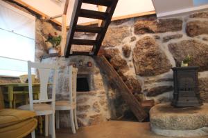 a room with a stone fireplace and a wooden ladder at Bosque dos Amieiros in Marco de Canaveses