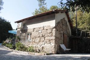 a small stone house with a chair in front of it at Bosque dos Amieiros in Marco de Canavezes