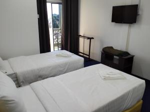 a hotel room with two beds and a television at MAIDAM Inn in Jertih