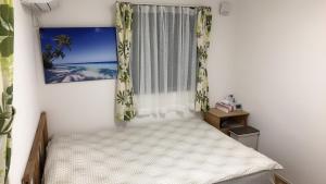 een kleine slaapkamer met een bed en een raam bij 竹内公寓 in Ichikawa