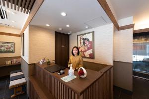 una mujer sentada en un escritorio en una habitación de hotel en Stay SAKURA Tokyo Asakusa Edo no Mai, en Tokio