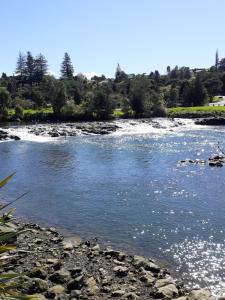a river with rocks in the water at J&D Cottage in Kerikeri