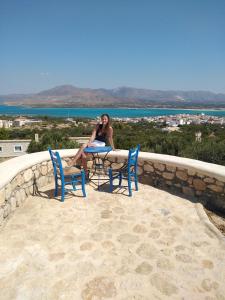 una donna seduta a un tavolo con due sedie di Studios Maniati a Elafónisos