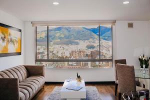 uma sala de estar com um sofá e uma grande janela em Olympus Apartments em Quito
