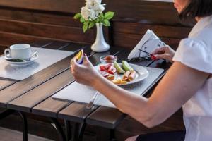 kobieta siedząca przy stole z talerzem jedzenia w obiekcie Hotel Marsen w mieście Winnica