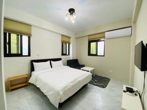 a bedroom with a white bed and a chair at Home of 120 B&B in Jiaoxi