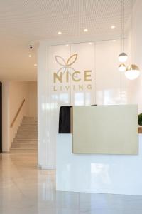 a white lobby with a nene living sign on a wall at Nice Living Neue- Moderne Apartments im Herzen von Brixen - kostenlose Brixencard - ideal für Familien, Paare, Geschäftsreisende, Gäste mit Hund und allen Urlaubs Hungrigen in Bressanone