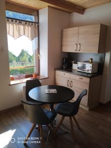 een keuken met een tafel en stoelen en een magnetron bij Les mimosas in La Bresse