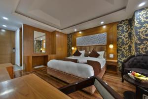 a bedroom with a large bed and a chair at The Montreal Srinagar A Unit Of Montreal Group in Srinagar