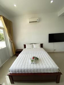 a bedroom with a large white bed with flowers on it at Con Dao Guesthouse in Con Dao