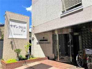 Un edificio con un cartel al costado. en Southern Cross Inn Matsumoto, en Matsumoto