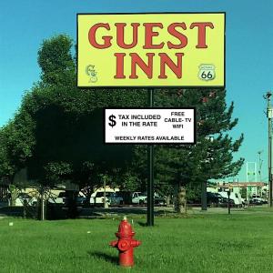 a sign for a guest inn next to a red fire hydrant at Guest Inn in Yukon