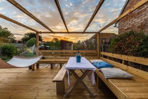 a patio with a hammock and a table and benches at Palm Bay Beach House in Margate