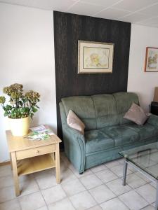 um sofá verde numa sala de estar com uma mesa em Südeifel Badem em Badem