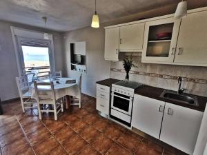 a kitchen with white cabinets and a table and a dining room at Casa Playa de Reheira in Camariñas