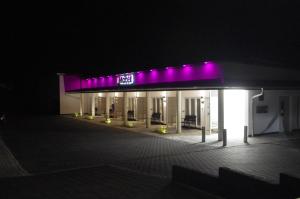un edificio con luci viola sopra la notte di CityMotel Ziegenhain a Schwalmstadt
