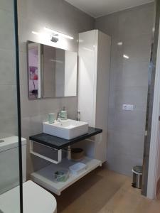 a white bathroom with a sink and a mirror at Garbí & Xaloc apartamentos in Cala Galdana