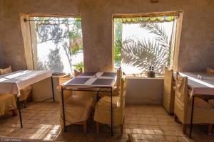 una sala da pranzo con due tavoli e due finestre di Siwa Shali Resort a Siwa
