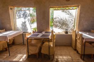 - une salle à manger avec deux tables et deux fenêtres dans l'établissement Siwa Shali Resort, à Siwa