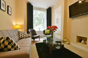 ein Wohnzimmer mit einem Sofa und einem TV in der Unterkunft Luxary 4 Bed, 4 bathroom house in central Burnley in Burnley