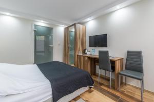 a bedroom with a bed and a desk and a television at Villa Pacyfic in Krynica Morska