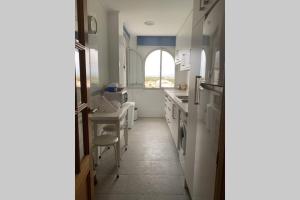 eine Küche mit einem Waschbecken, einem Tisch und einem Fenster in der Unterkunft apartamento con vistas valdelagrana in El Puerto de Santa María