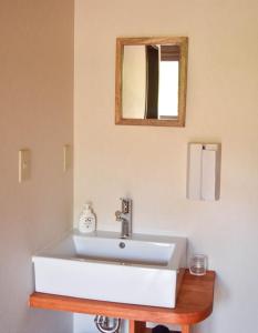 lavabo blanco en el baño con espejo en Hostel&Cafe Farolito en Ukiha