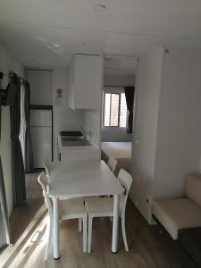 a kitchen with a table, chairs and a refrigerator at Camping Village Il Gineprino in Marina di Bibbona