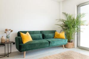 
a green couch sitting in a living room next to a window at The Olive - Boutique Apartment Hotel and Spa in Cala Llonga
