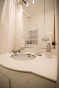 a white bathroom with a sink and a mirror at Via Dei Cartari Luxury Appartament in Rome