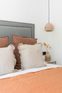 een bed met bruine en witte kussens en een hanger bij The Olive Boutique Suites & Spa in Cala Llonga