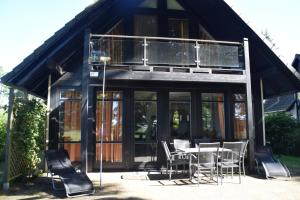 ein Haus mit einem Balkon, einem Tisch und Stühlen in der Unterkunft Ferienhaus Plau am See, direkt am Wasser in Plau am See