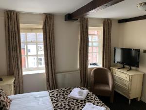 a hotel room with a bed and a flat screen tv at The Silk House in Leek