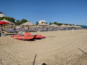 una barca rossa su una spiaggia con sedie e ombrelloni di Hotel Nel Pineto a Montesilvano