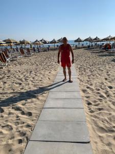 Un uomo in piedi sulla spiaggia di Hotel Nel Pineto a Montesilvano