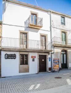 a white building with two balconies on a street at Albergue San Anton in Melide