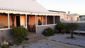 a house with a porch and some bushes at Port Nolloth Beach Shack in Port Nolloth