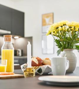 a table with a cup of orange juice and a vase of flowers at Glücksferien- Sonnenhut in Glücksburg