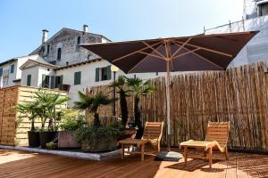 un patio con 2 sillas y una sombrilla en Hotel and Wellness Patriarca, en San Vito al Tagliamento