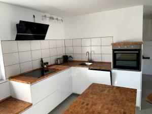 - une cuisine avec des placards blancs et un évier dans l'établissement Ferienwohnung im Stadtzentrum, à Hennigsdorf
